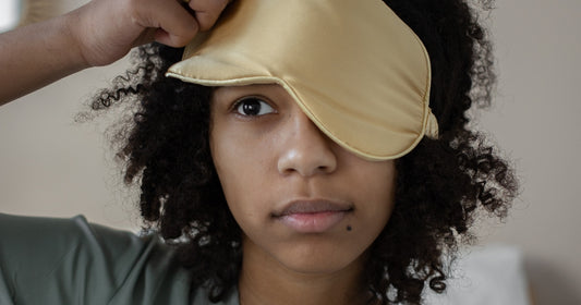 A woman pulling up a sleep mask after a full night's rest.